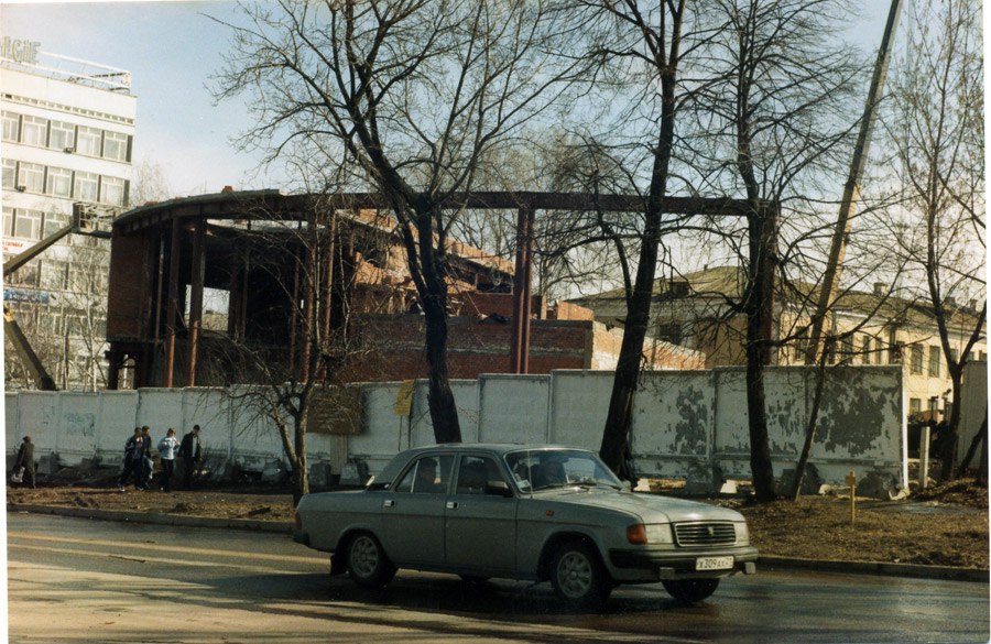 На этом изображении видно, как днем по улице едет машина. Автомобиль выглядит как седан среднего...